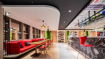 A modern restaurant with red seating, wooden tables, and a green wall.