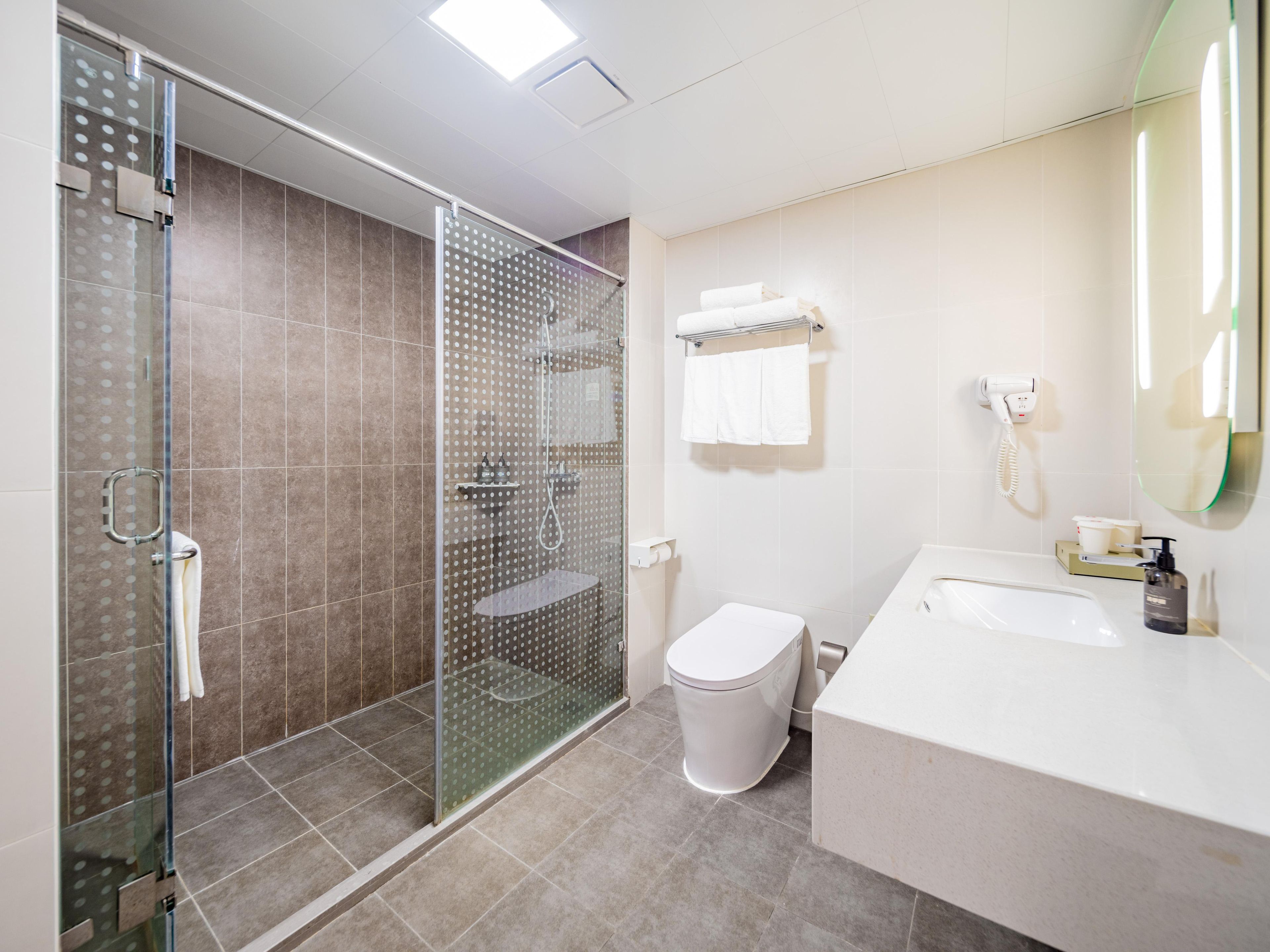 Un bagno moderno con doccia a vetro, un water, un lavandino con specchio e un porta asciugamani.