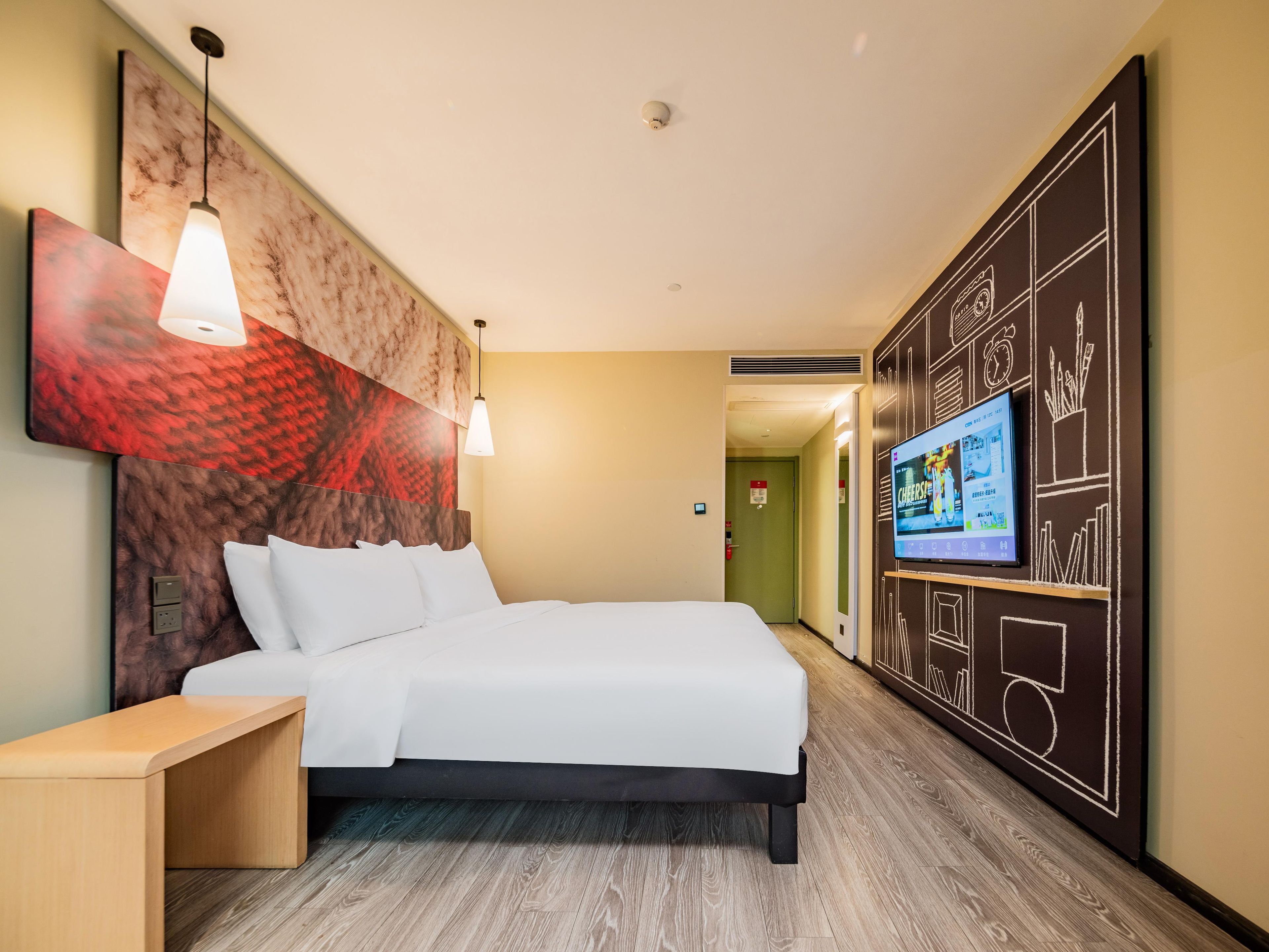Ein modernes Hotelzimmer mit einem großen Bett, Nachttisch, Wand-TV und einem einzigartigen Kunstwerk an der Wand.
