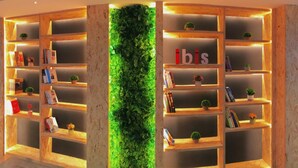 A modern library with wooden bookshelves and a green vertical garden. - Ibis Chengdu Kuanzhai Alley Center Hotel (Chengdu)