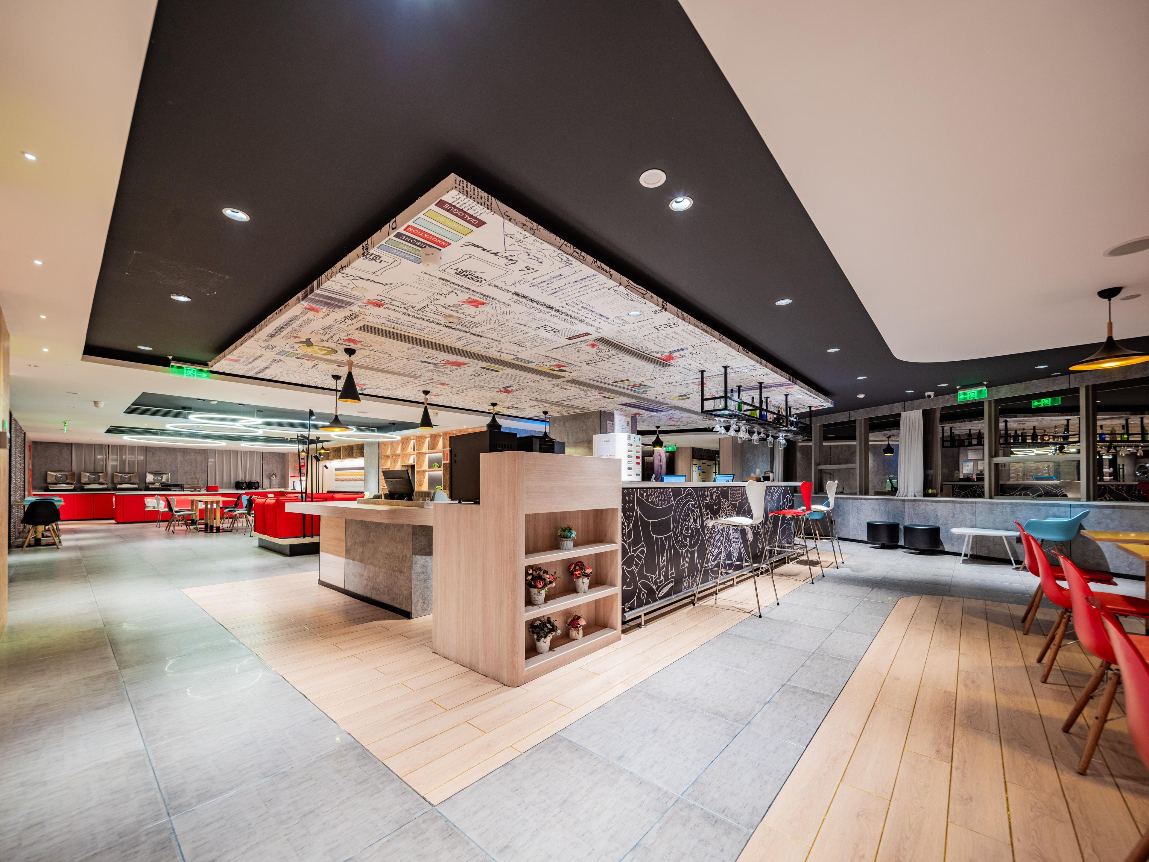 Un interno ristorante moderno con un'area bar centrale, posti a sedere e un soffitto con decorazioni artistiche.