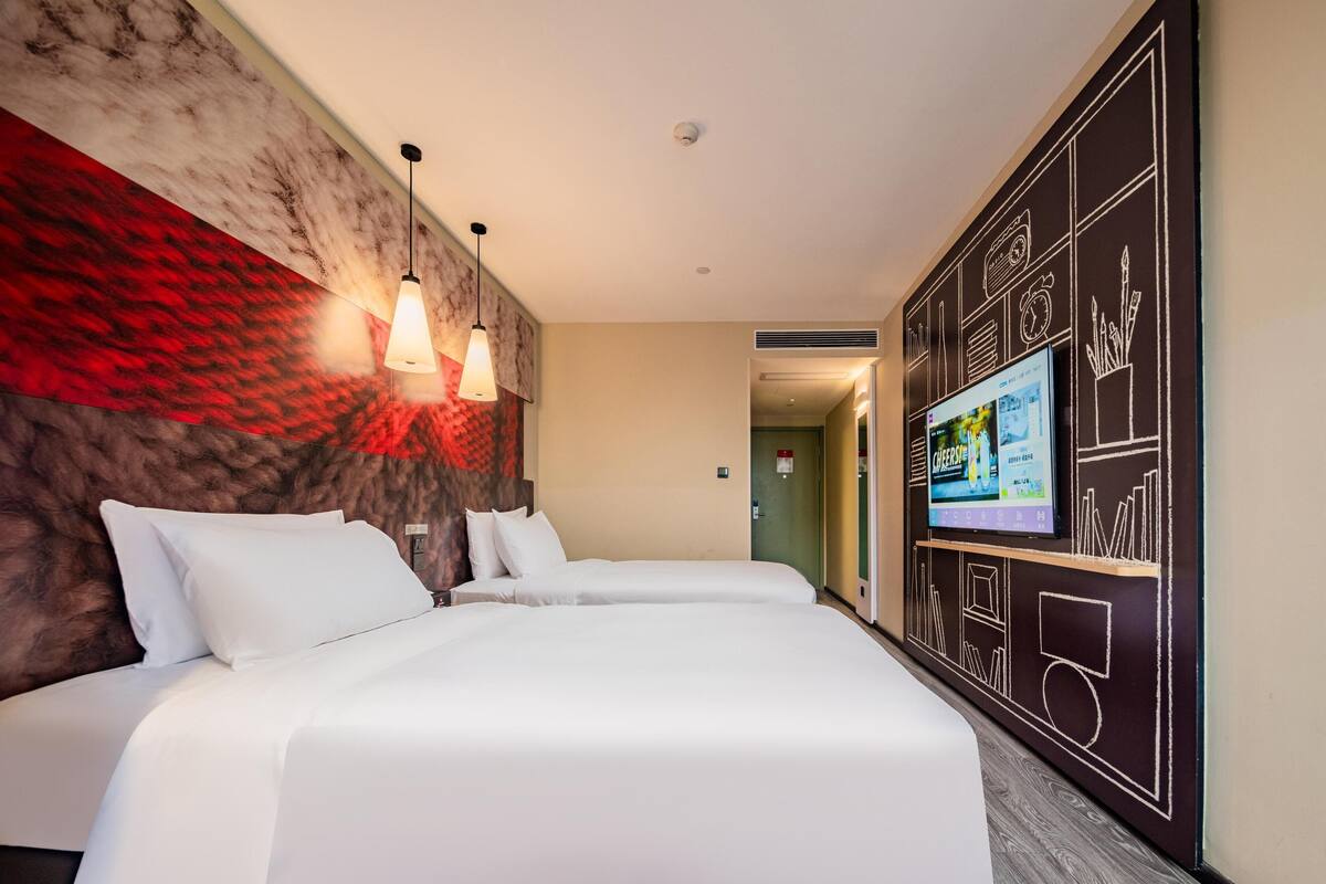 Una habitación de hotel con una cama grande, dos lámparas de noche, un televisor en la pared y una pared texturizada en tonos rojo y marrón.