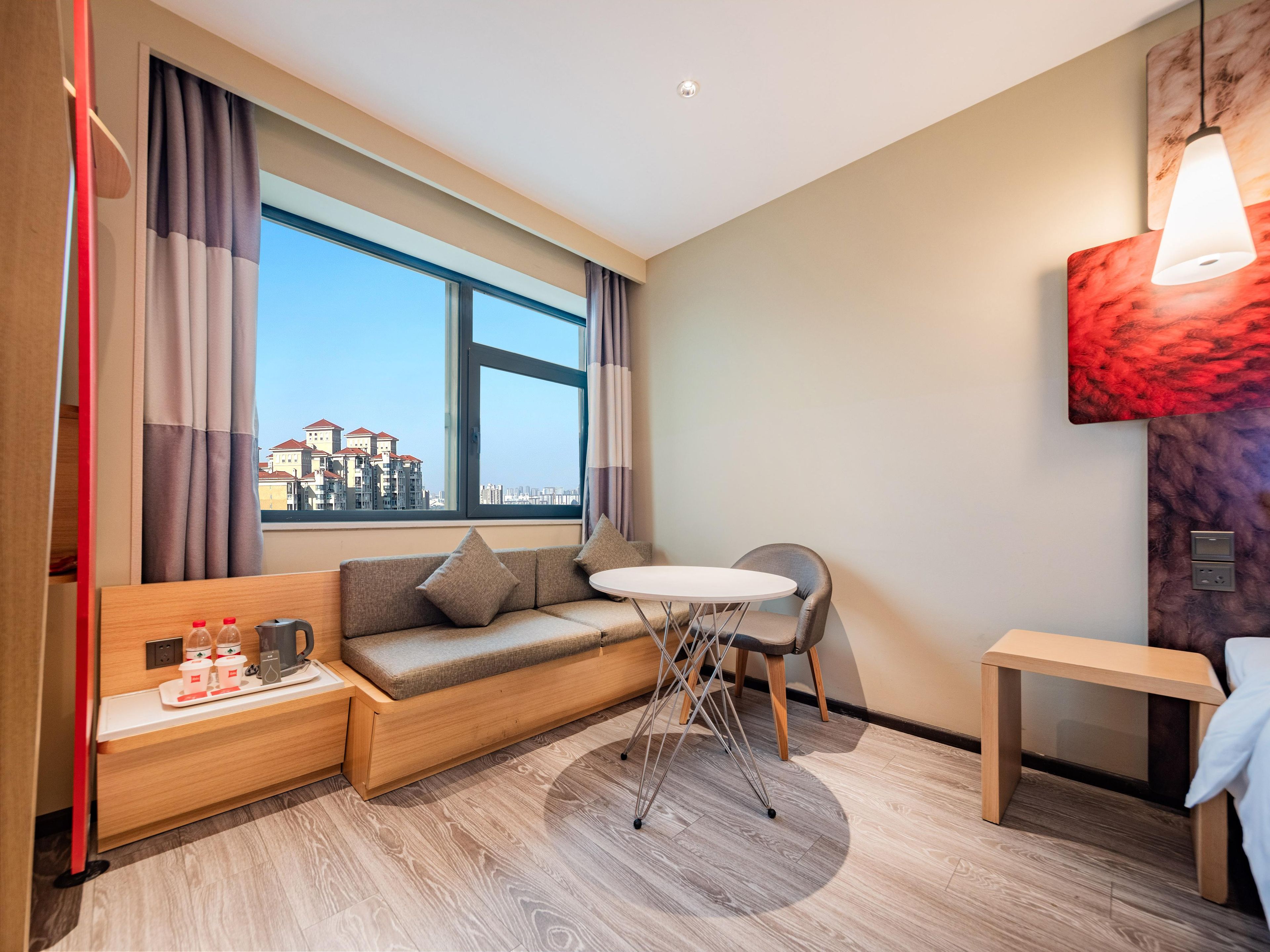 Habitación de hotel con sofá, una mesita, una silla, una mesa redonda y vistas a la ciudad.
