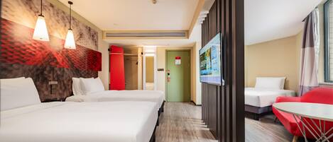A hotel room with two beds, a TV, a red chair, and a small table.