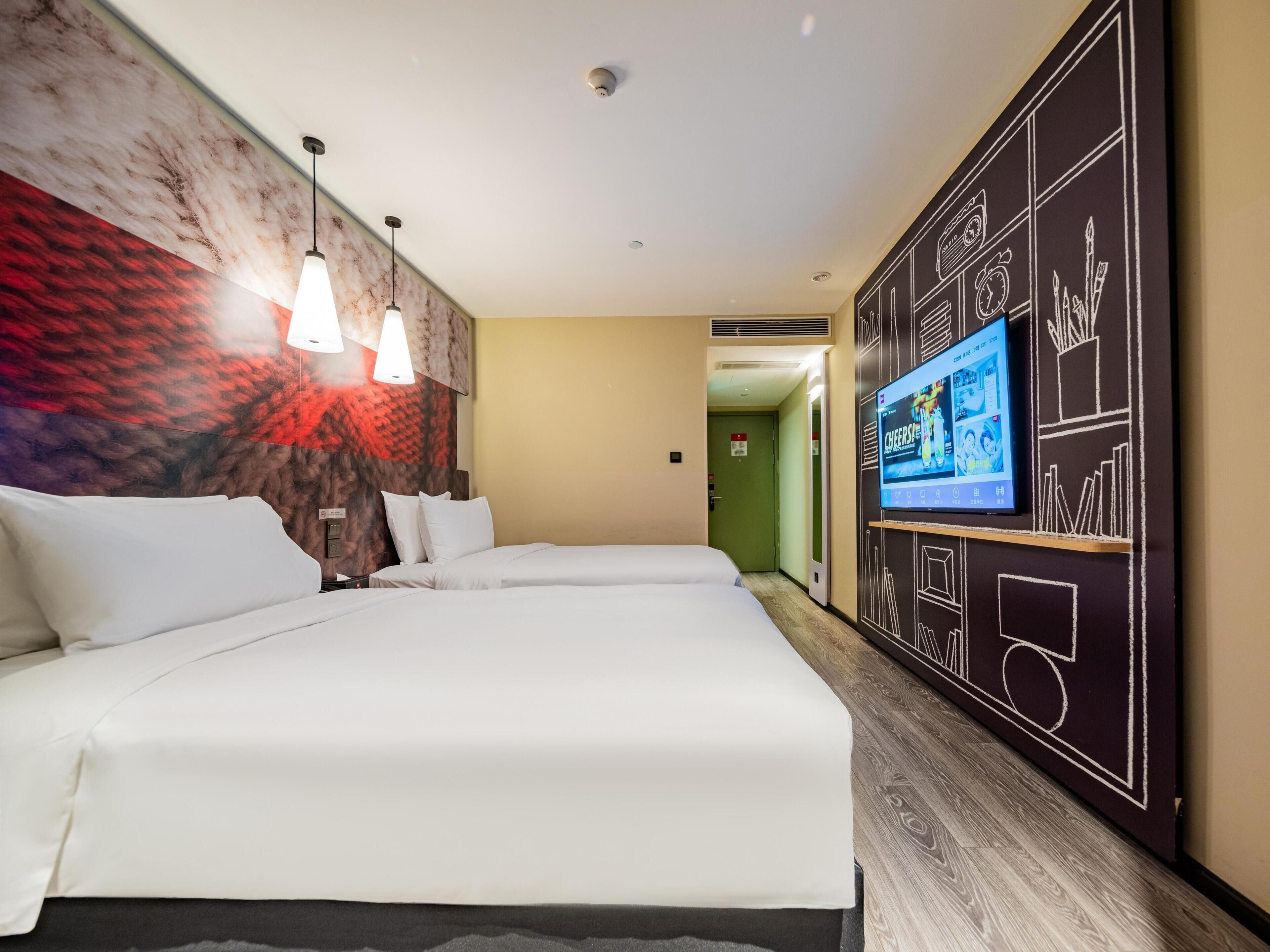 Een hotelkamer met twee bedden, een televisie aan de muur en een muurschildering.