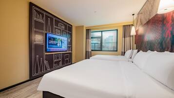Habitación de hotel con una cama grande, un televisor de pantalla plana montado en una pared negra, una ventana con cortinas y vistas a la ciudad.