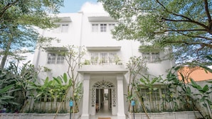 A white building with a central entrance, surrounded by greenery and a paved area. - Umalas Suites Bali (Kerobokan)