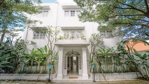 A white building with a central entrance, surrounded by greenery and a paved area. - Umalas Suites Bali (Kerobokan)