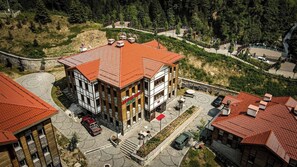 Un hotel con tejado de tejas rojas, un patio con mesas al aire libre y vistas a una cascada.