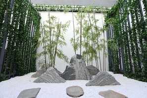 A Zen garden with rock formations, bamboo, and a white gravel path.