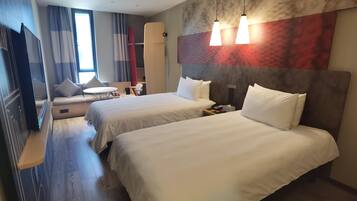 A hotel room with two beds, a TV, a desk, and a chair.