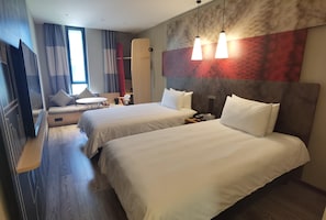 Habitación de hotel con dos camas, un televisor, un escritorio y una silla.
