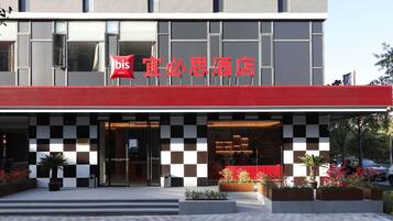 A hotel with a red and black checkered facade, a visible entrance, and potted plants in the foreground.