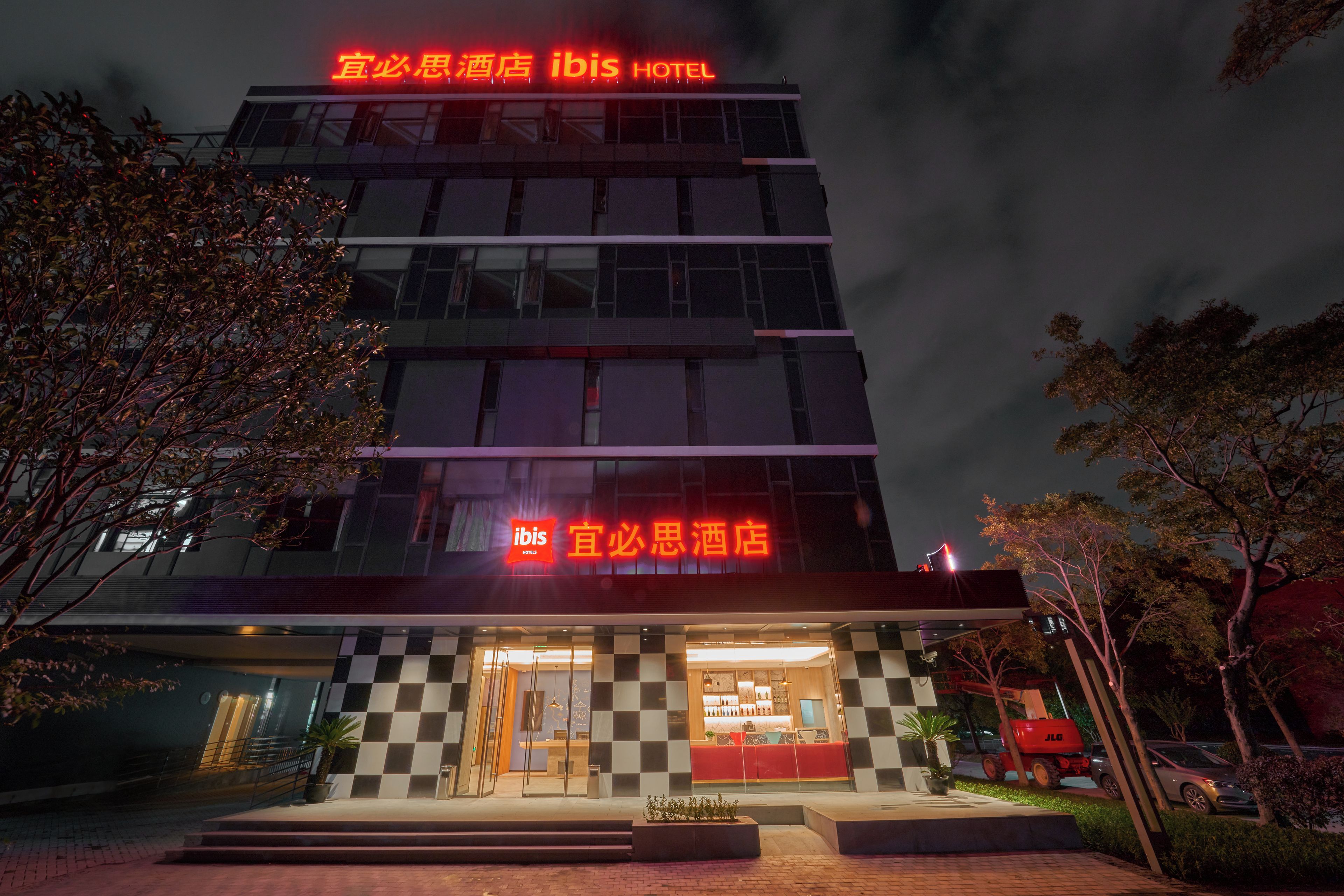 Un hotel con fachada a cuadros, letreros iluminados y una entrada visible.