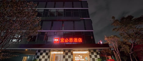 Un hotel con fachada a cuadros, letreros iluminados y una entrada visible.