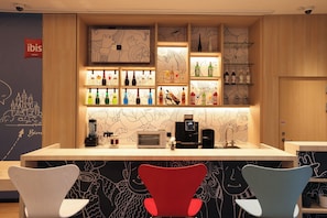 A bar area with shelves of bottles, a coffee machine, and a toaster. There are chairs with a unique design.
