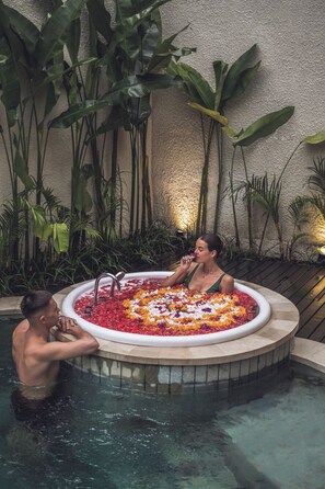 Un bain à remous entouré d’une végétation luxuriante et adossé à un mur à la texture intéressante.