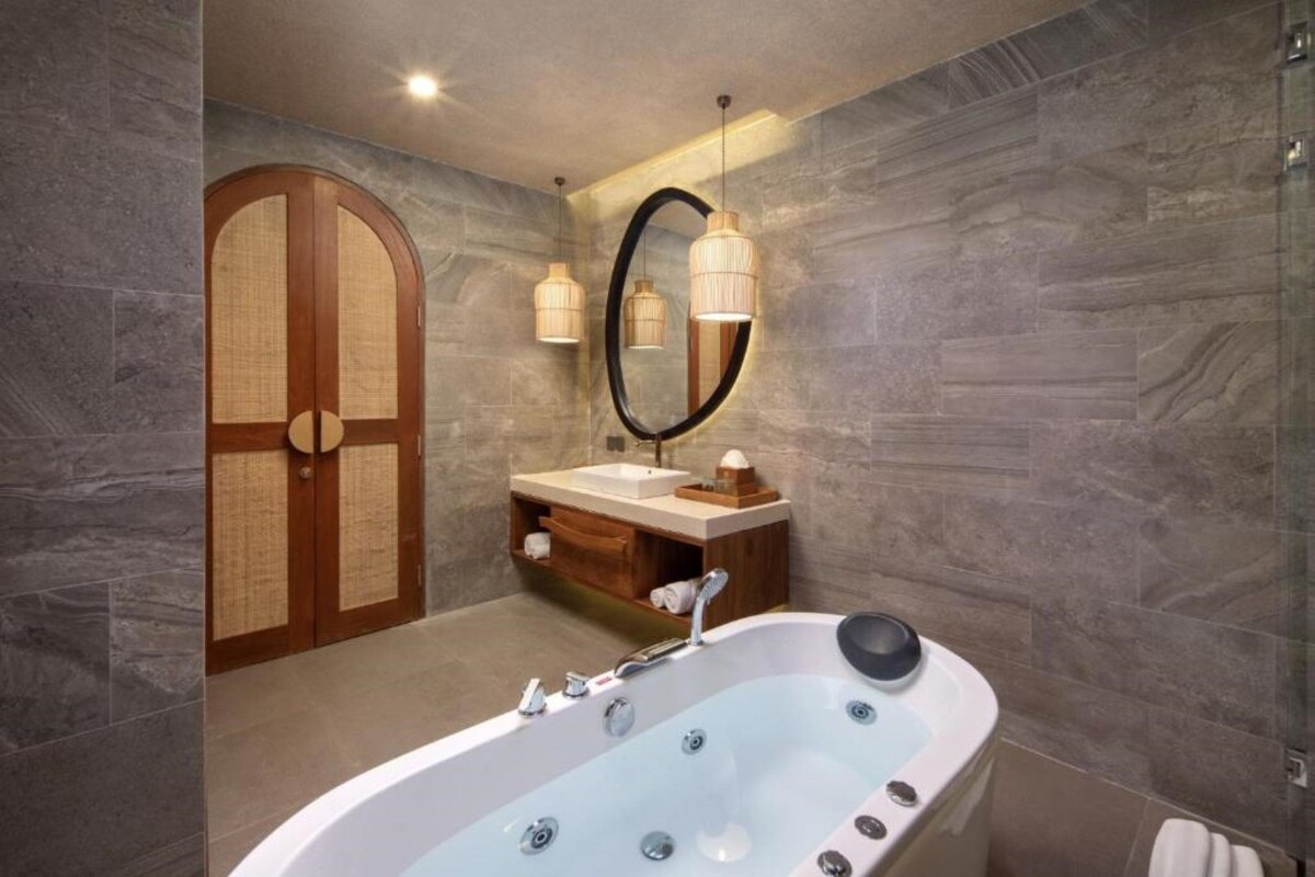 A modern bathroom with a freestanding bathtub, a vanity with a mirror, and a wooden door.
