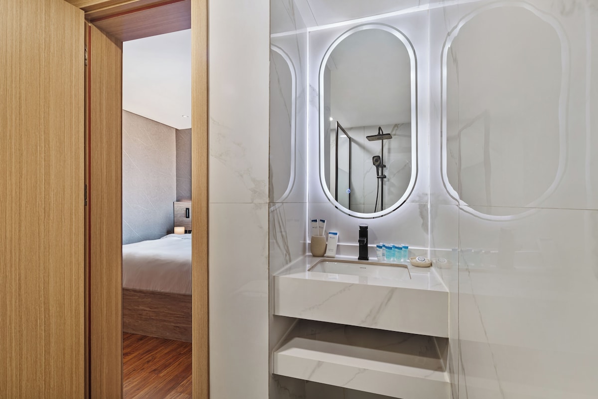 A modern bathroom with a marble vanity, a large mirror, and a shower area.