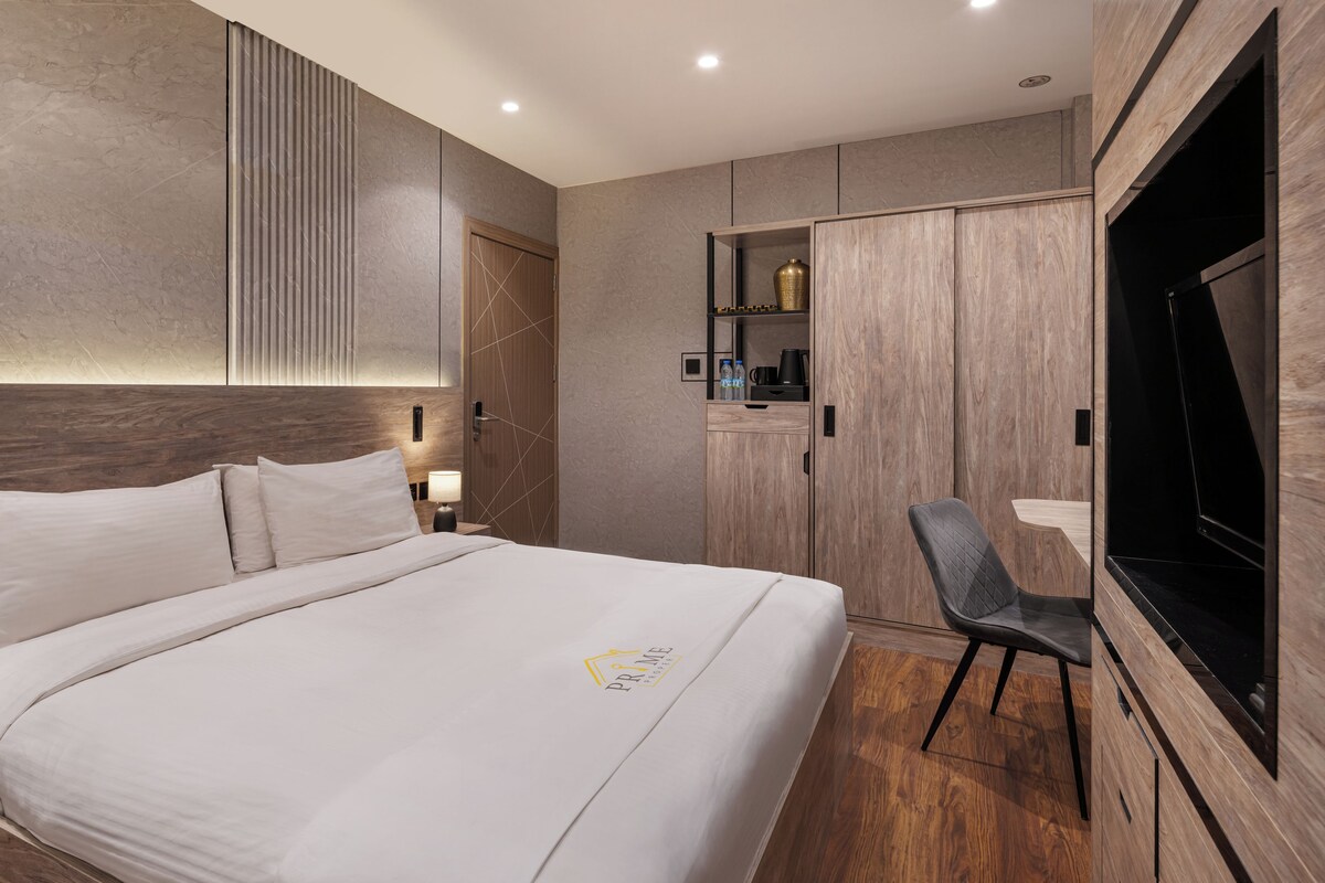 Una habitación de hotel moderna con una cama grande, televisión de pantalla plana, armario y zona de escritorio.