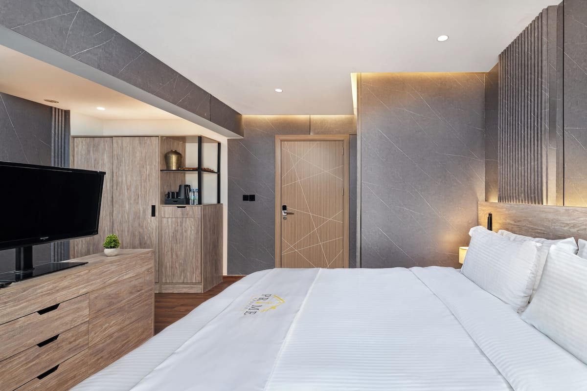 Un dormitorio moderno con cama, televisor, armario de madera y estanterías empotradas.