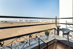A balcony with a view of a construction site, a potted plant, and a white chair. - Regency Inn Hotel Oman (Muscat)