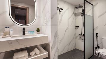 A bathroom with a marble vanity, a round mirror, a shower enclosure, and a toilet.