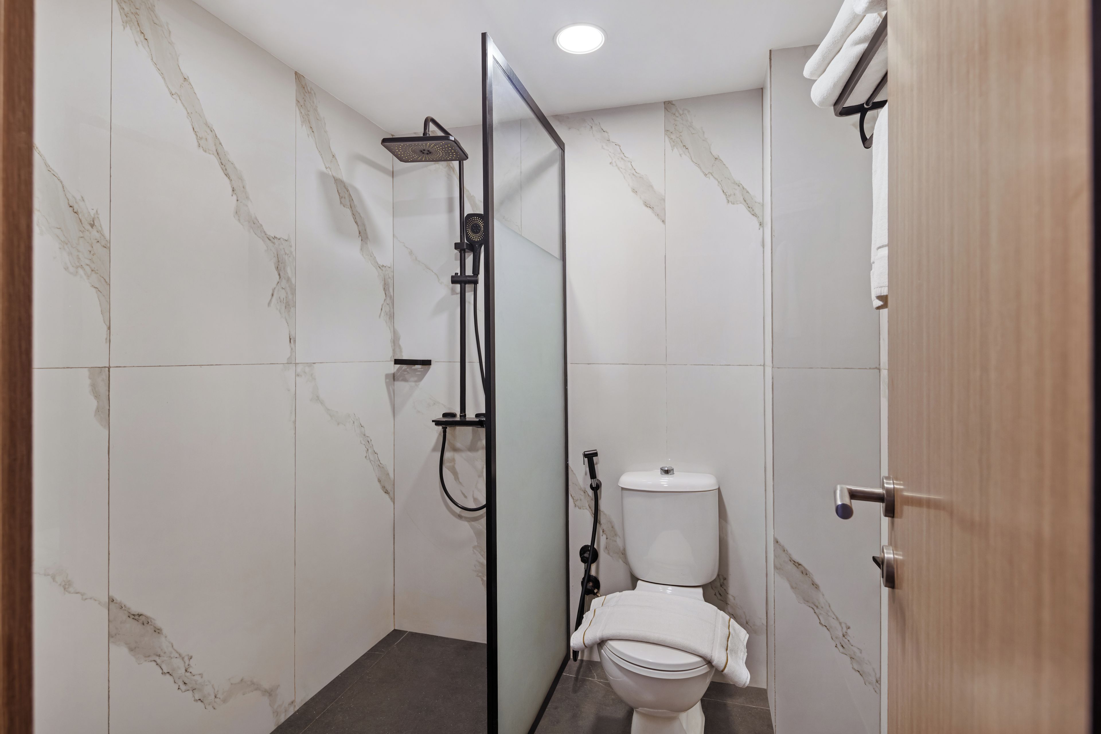 Un baño con ducha, inodoro y mampara de vidrio.