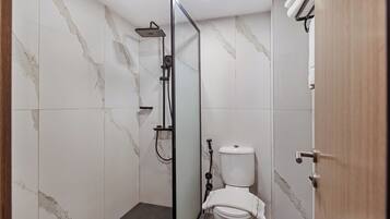 Un baño con ducha, inodoro y mampara de vidrio.