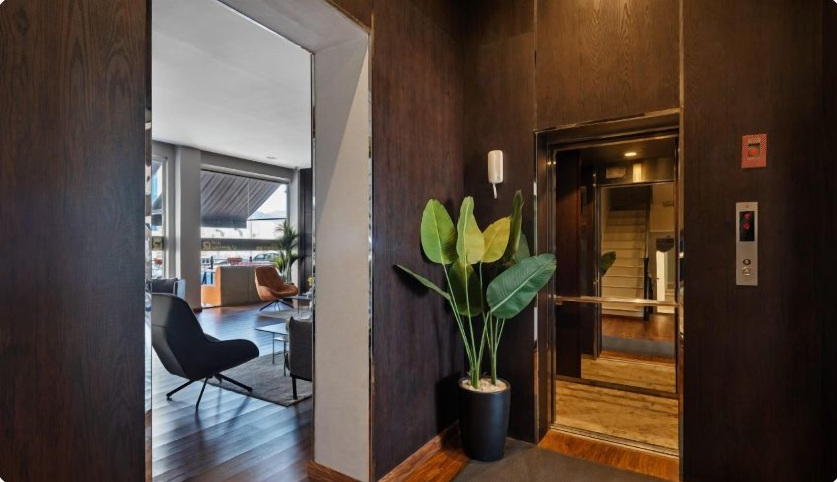 Un interior moderno con suelo de madera, una planta en maceta y un ascensor.