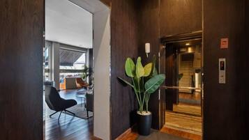 Un interior moderno con suelo de madera, una planta en maceta y un ascensor.