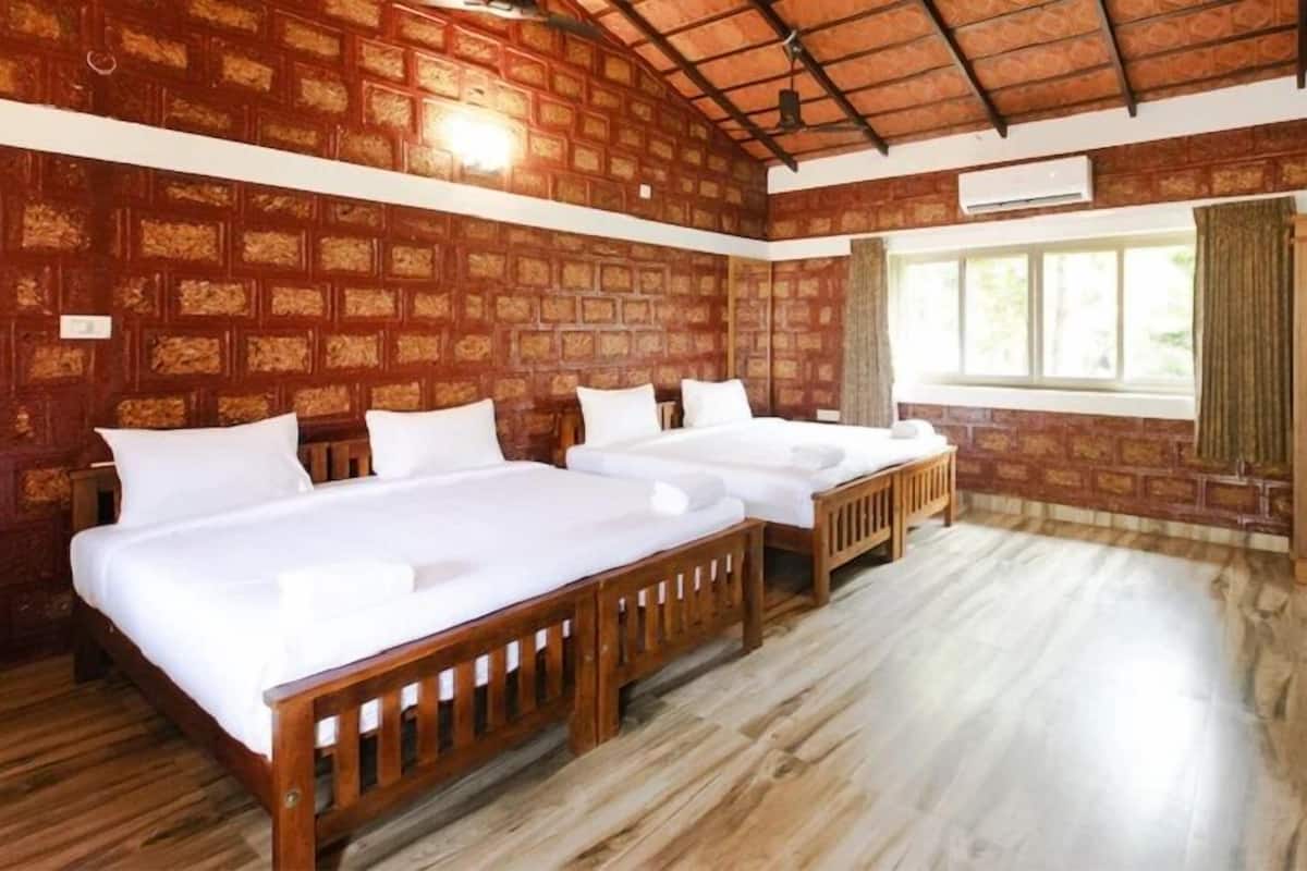 Una habitación con dos camas, una ventana y techo de madera.