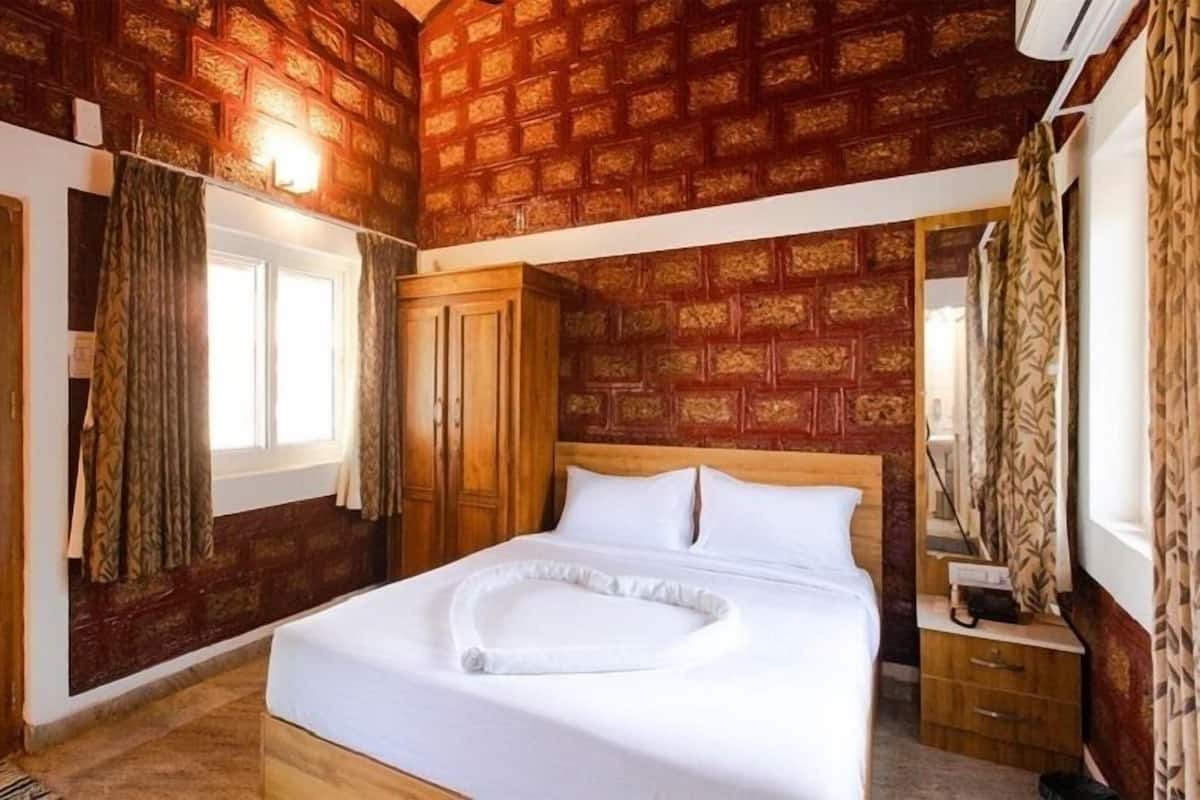 Un dormitorio con cabecera de madera, cama con ropa de cama blanca, armario de madera y ventana con cortinas.