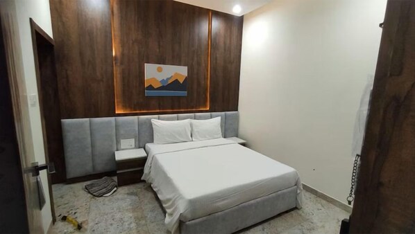 Un dormitorio con una cama, mesitas de noche, una obra de arte en la pared y una puerta.