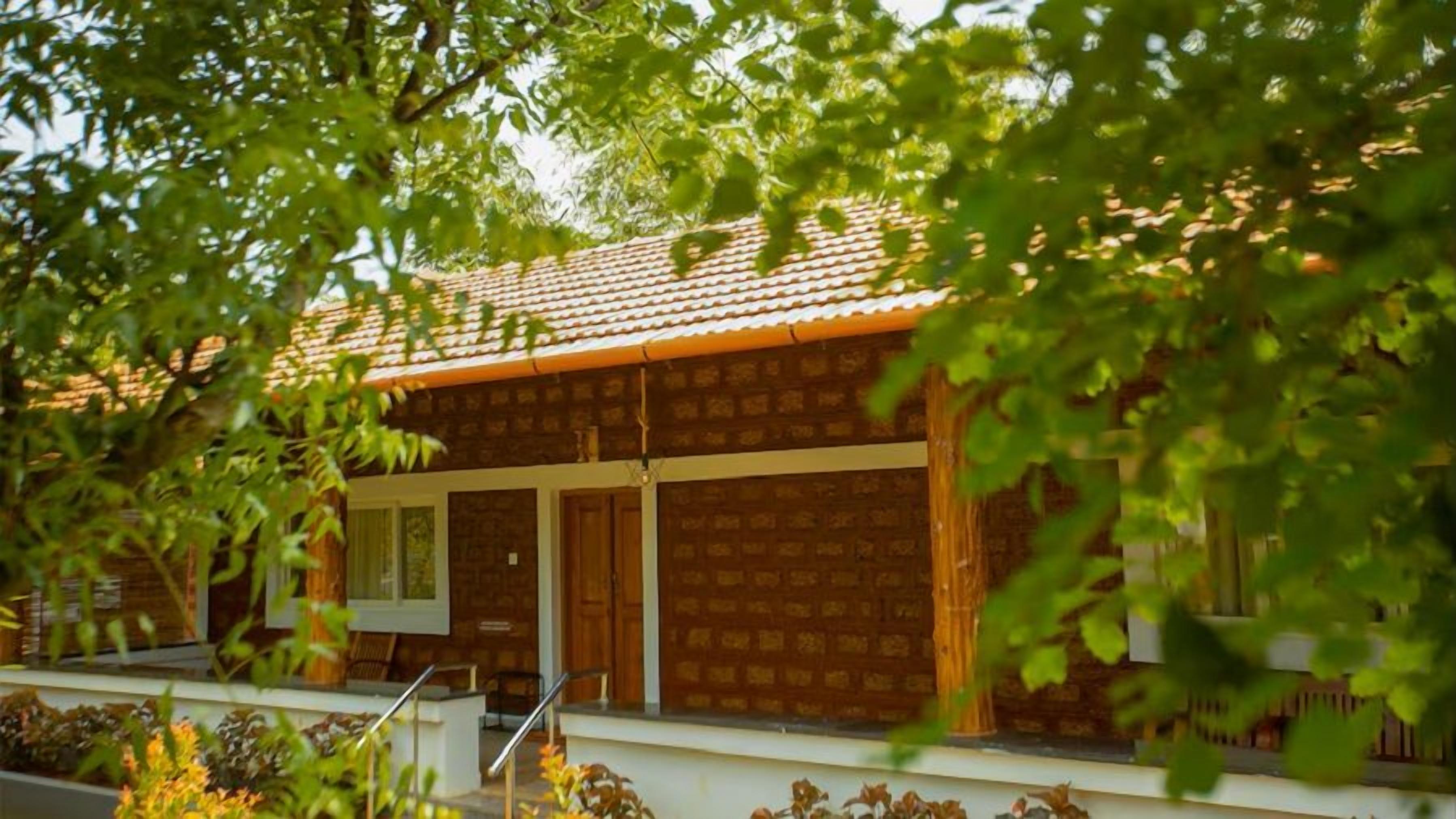 A two-story building with a tiled roof, a front porch, and a garage.
