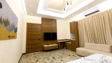Une chambre d’hôtel moderne équipée d’un téléviseur à écran plat, d’un canapé, d’une armoire en bois et d’un tableau accroché au mur.