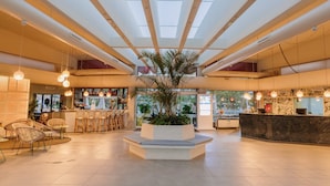 A spacious lobby with a central planter, seating area, and a reception desk. - Maspalomas Villas By Dunas (San Bartolomé de Tirajana)