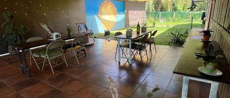 A spacious room with a large window, a dining area with chairs and a table, and a wall with a mural.