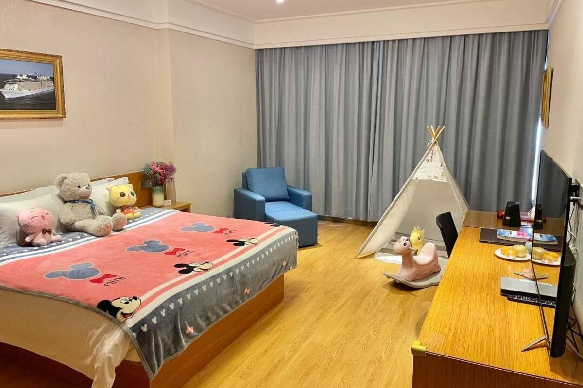 Una habitación de hotel con una cama, una silla azul, un tipi y un escritorio con un ordenador.