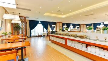 Un comedor de hotel con mesas de madera, una barra de buffet y vistas al exterior.