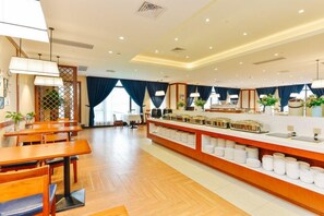 Un comedor de hotel con mesas de madera, una barra de buffet y vistas al exterior.
