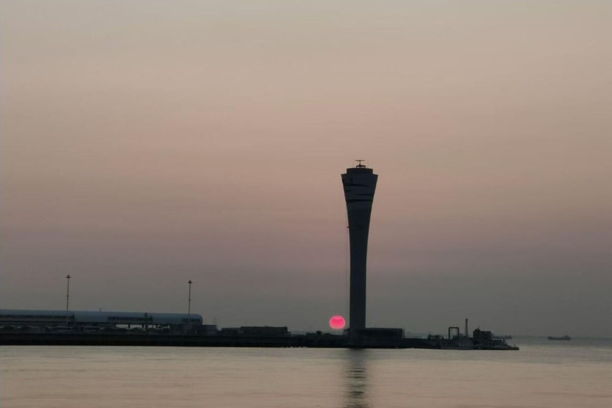 A tall tower structure near a body of water with a sunset in the background.
