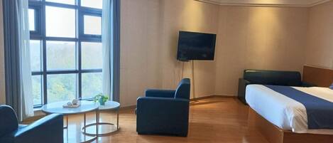 Une chambre d’hôtel avec un lit, une télévision, une petite table et une chaise.