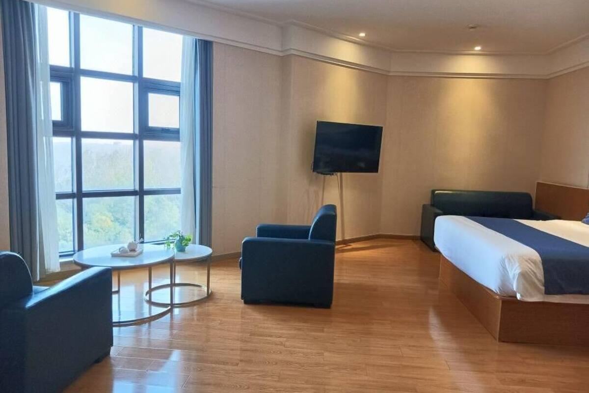 Una habitación de hotel con una cama, televisión, una mesita y una silla.
