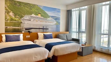 Habitación de hotel con dos camas, un ventanal con cortinas y un mural de un barco crucero.