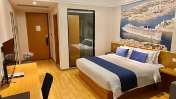 Habitación de hotel con cama, escritorio, silla, puerta corrediza y un cartel grande en la pared.