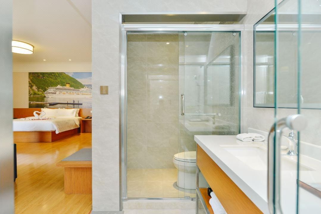 A modern bathroom with a glass shower enclosure, a white sink, and a large mirror.