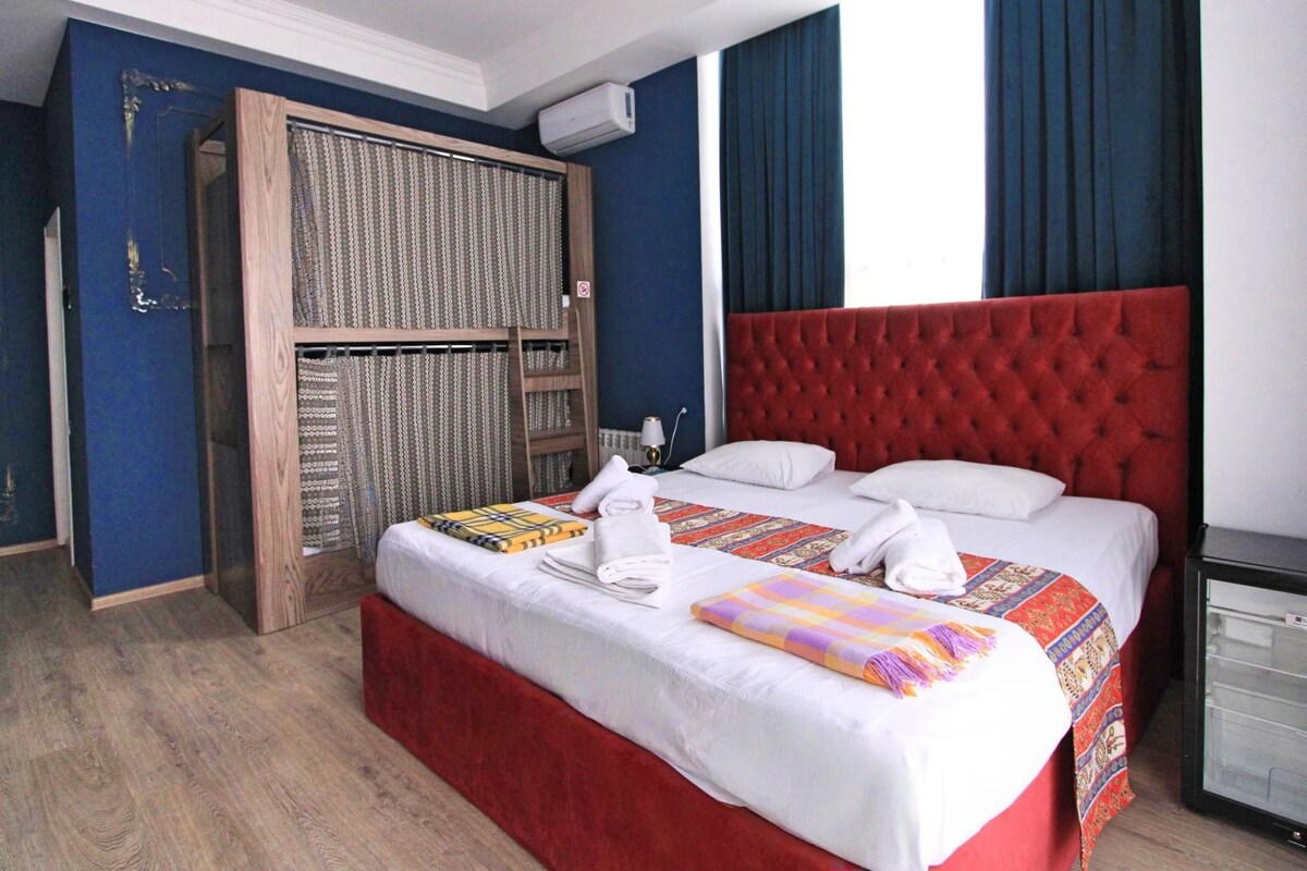 Une chambre d’hôtel avec un grand lit, une armoire et un petit réfrigérateur.