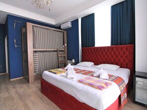 Une chambre d’hôtel avec un grand lit, une armoire et un petit réfrigérateur.