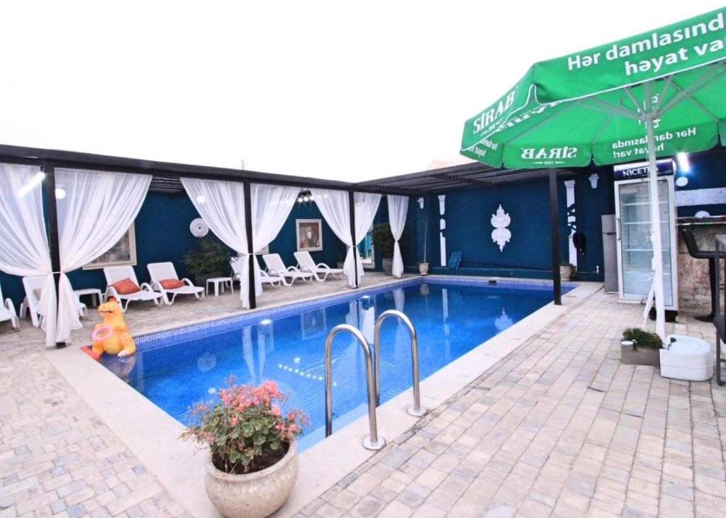 A swimming pool with lounge chairs, a covered seating area, and a sign with text.